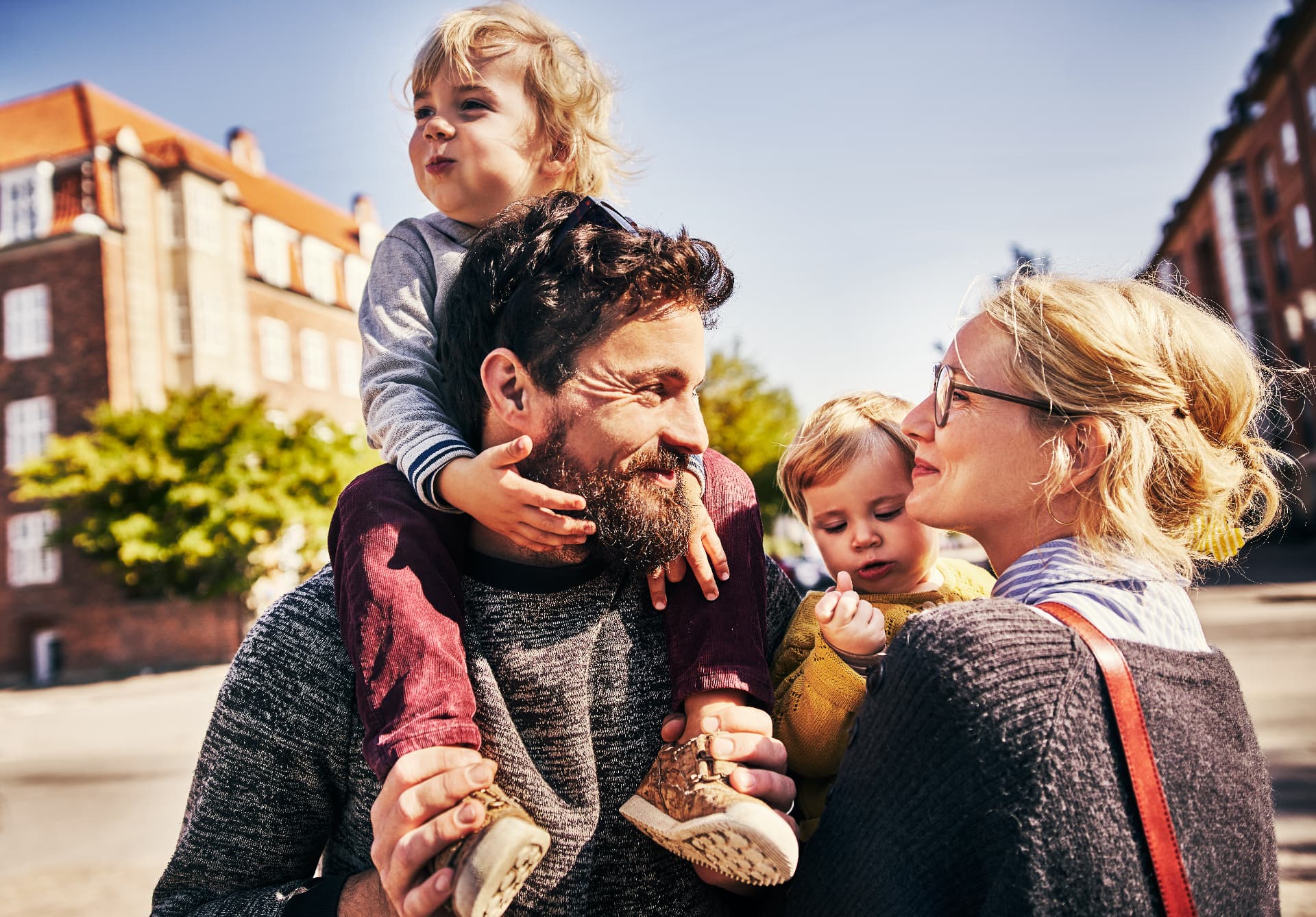 Familj med barn på axlarna på en stadsgata