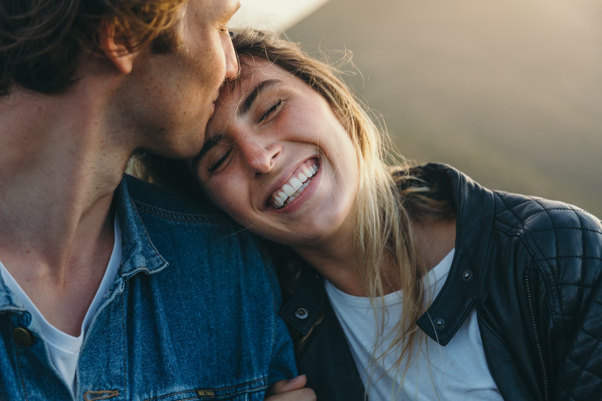 A couple laughing close together outdoors