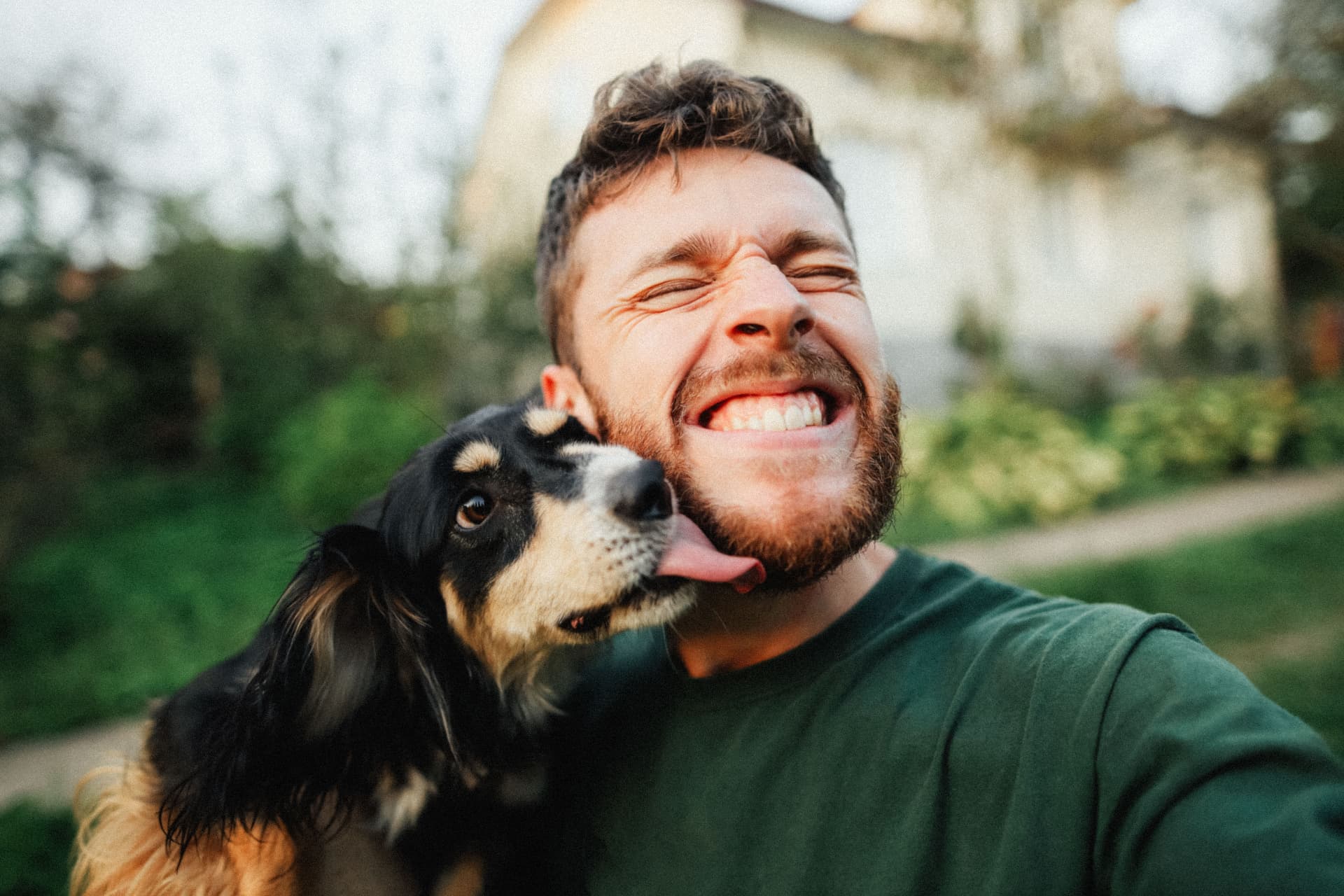 Skrattande man som får en puss av sin hund